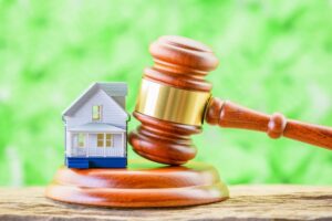 Legal issues in real estate transactions. A small model house and a judge's gavel placed near each other. 