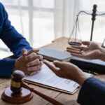 Attorneys discuss legal details with clients in an office setting. Close-up of a judge's gavel and a lawyer consulting on a legal case.