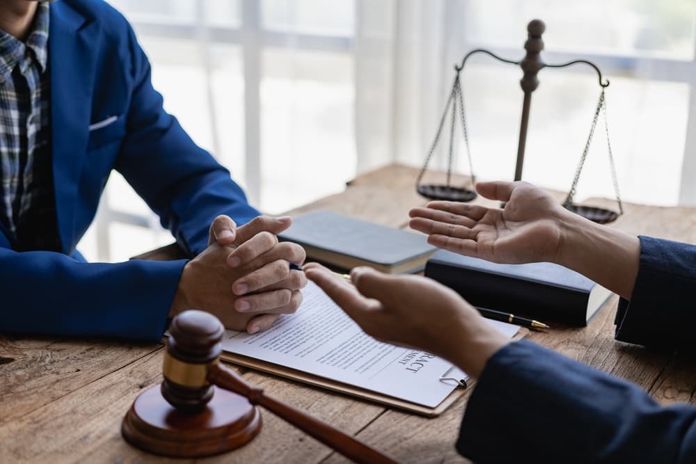 Attorneys discuss legal details with clients in an office setting. Close-up of a judge's gavel and a lawyer consulting on a legal case.