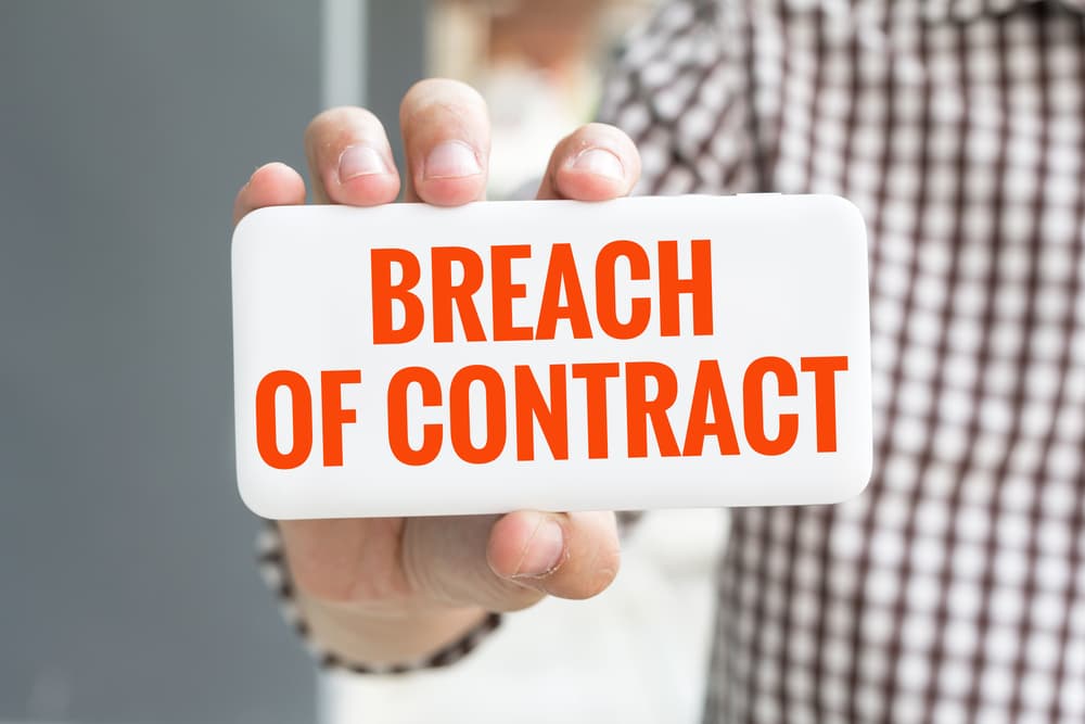 The lawyer is consultinMan hand showing BREACH OF CONTRACT word 