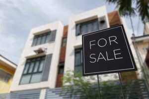 For sale sign in front of an affordable three storey apartment building.