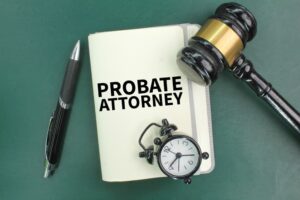 A pen, a judge's gavel, an alarm clock and a book with the words probate attorney. 