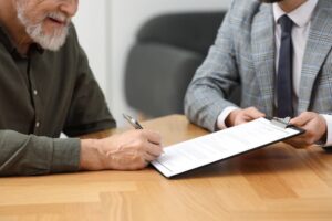 Probate Lawyer showing senior man where to sign Last Will and Testament