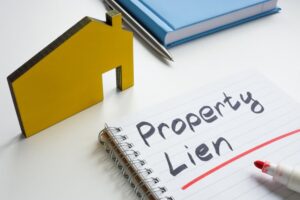 Property lien. Small house and writing in a notebook.
